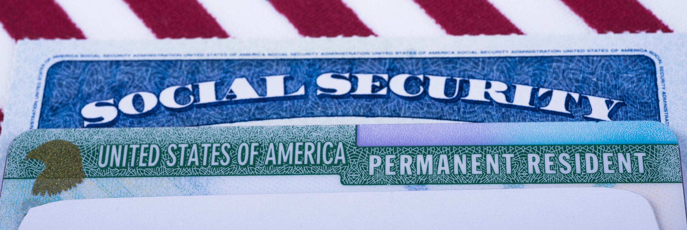 United states of America Permanent Resident  (Green card) and Social security number (SSN) cards on USA Flag background.